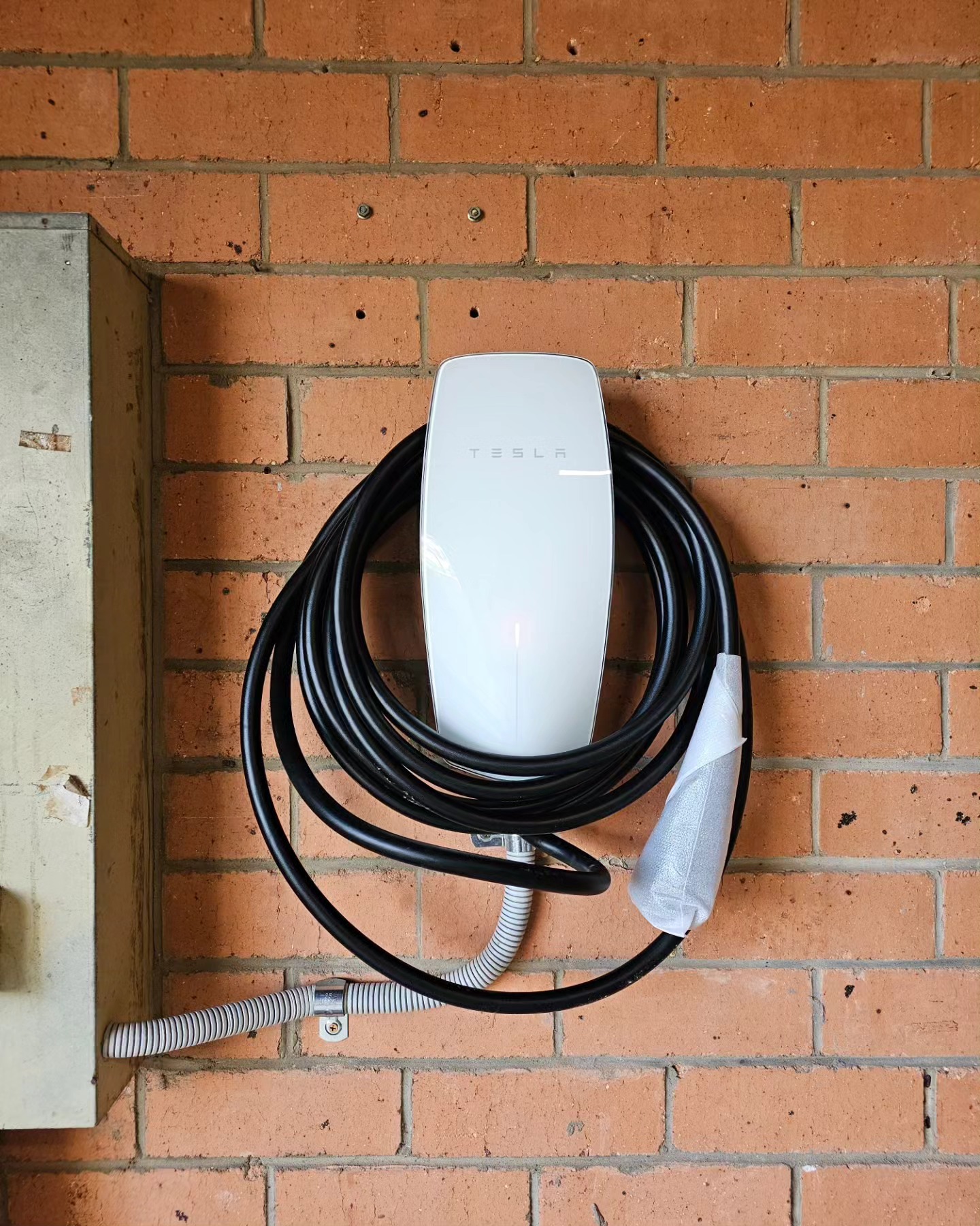 Tesla Wall Connector on brick wall — residential Brisbane