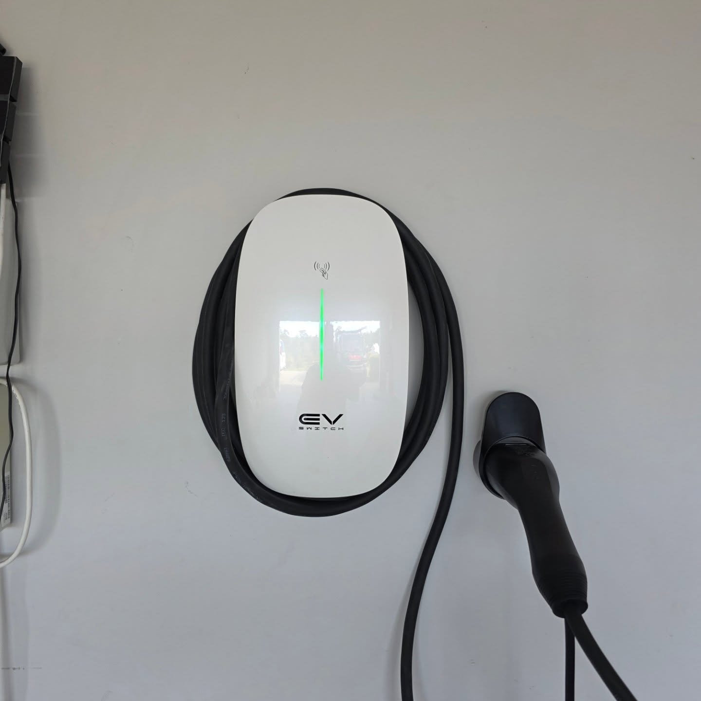 EV Switch charger — white oval, garage wall mount